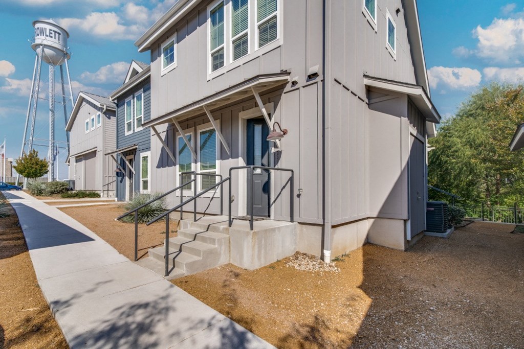 Apartments in Rowlett, TX - Village of Rowlett - Exterior View of Apartment Buildings with Concrete Stairs and Elevated Water Storage Tank in the Background