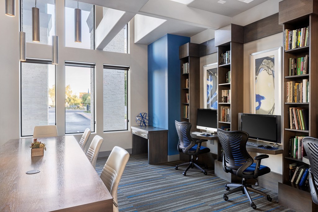 a room with a desk and chairs and a library
