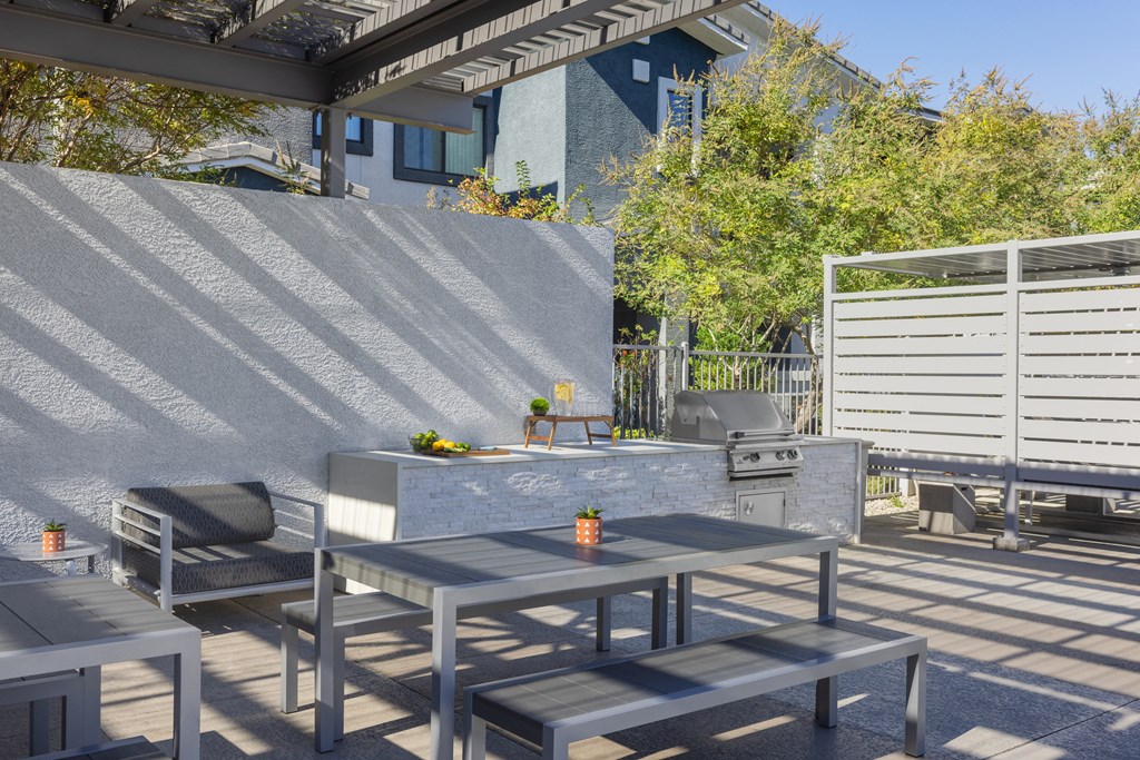a patio with a table and chairs and a grill
