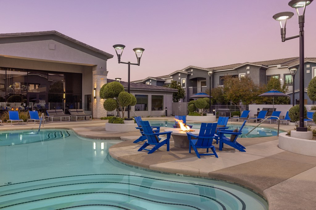 a swimming pool with blue chairs around a table