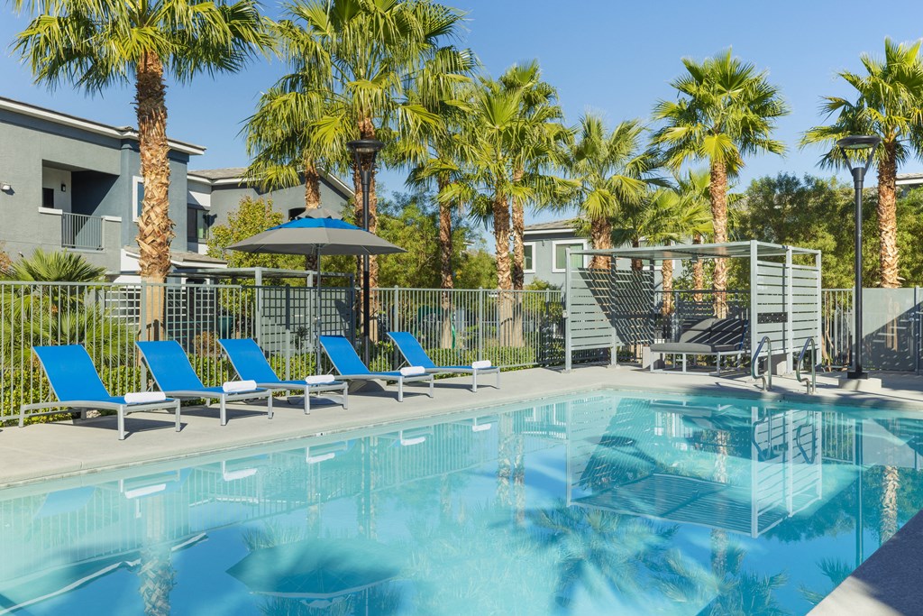 a swimming pool with blue lounge chairs and palm trees