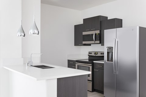 A modern kitchen with a white countertop and stainless steel appliances.