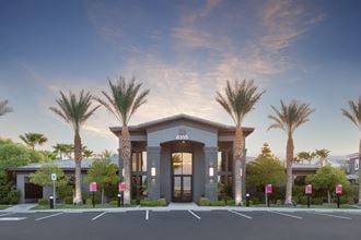 a parking lot with palm trees in front of a building