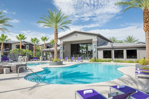 a swimming pool with purple chairs and a building with palm trees