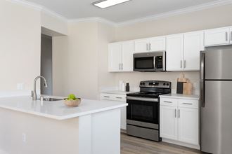a kitchen with white cabinets and stainless steel appliances and a white counter top