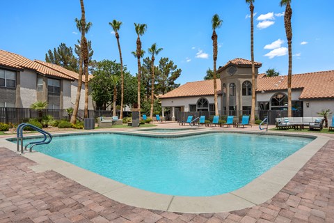 A swimming pool surrounded by palm trees and a building in the background.