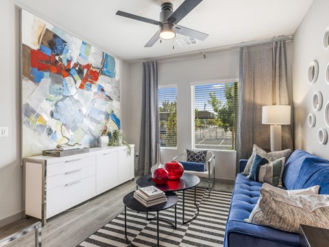 A living room with a blue couch and a black and white striped rug.