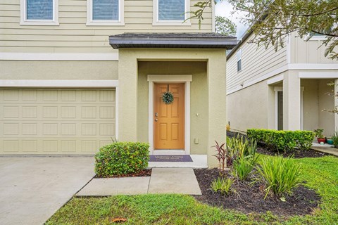 A house with a brown door and a small garden in front.