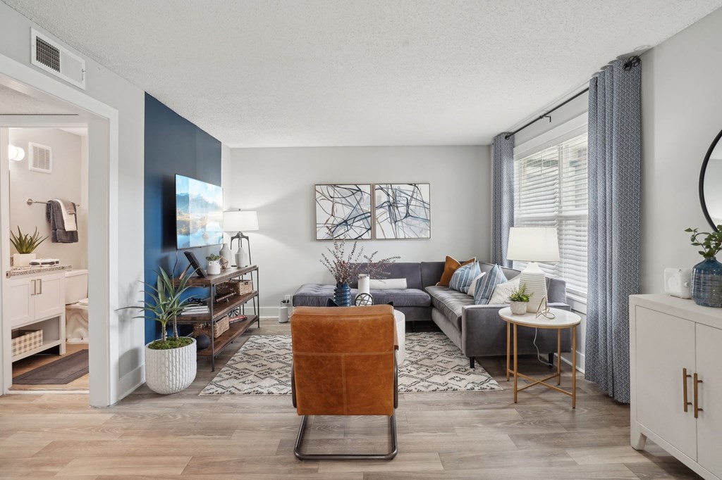 Modern living room with gray sectional, leather chair, and blue accent wall.