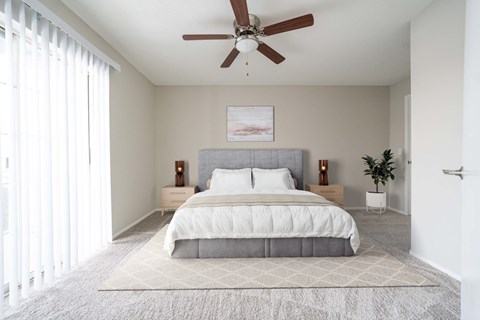 A bedroom with a large bed and a ceiling fan.