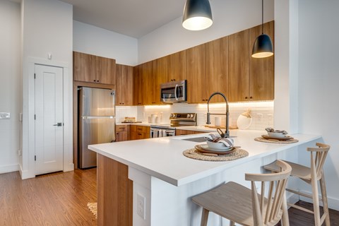 A kitchen with a white counter top and wooden cabinets.
