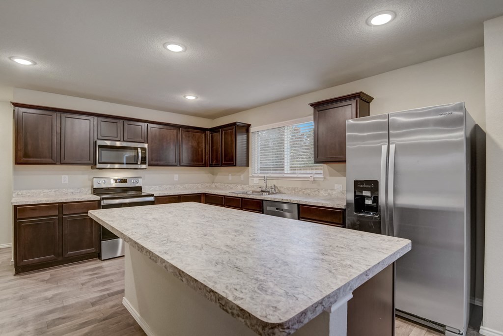 an updated kitchen with stainless steel appliances and a marble counter top