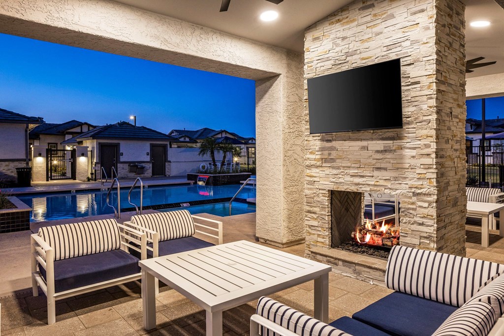 A patio with a stone fireplace and a television mounted above it.