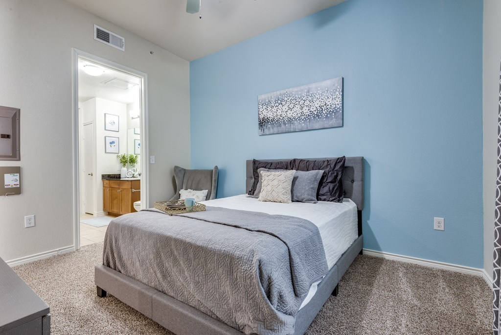 a bedroom with a bed and a blue wall and a door to a bathroom