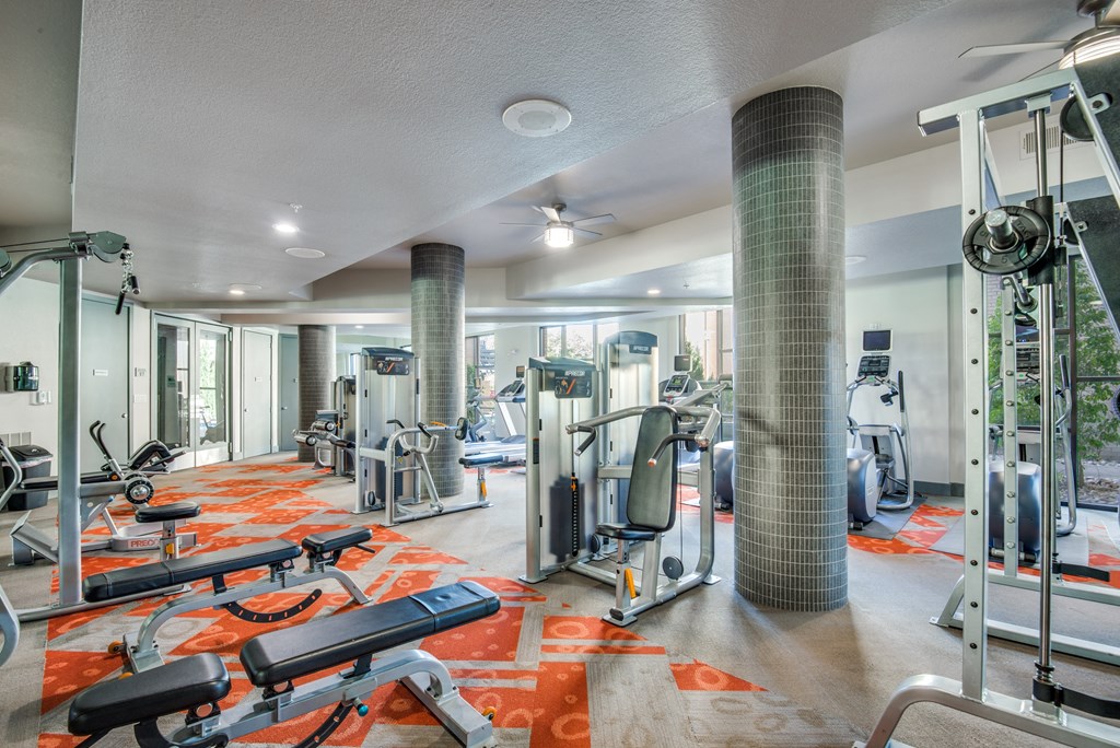 a gym with cardio equipment and weights in a building with glass doors