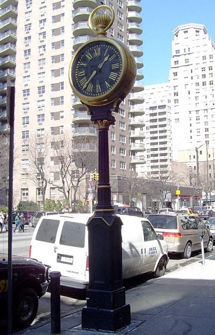 a clock on a pole on a city street