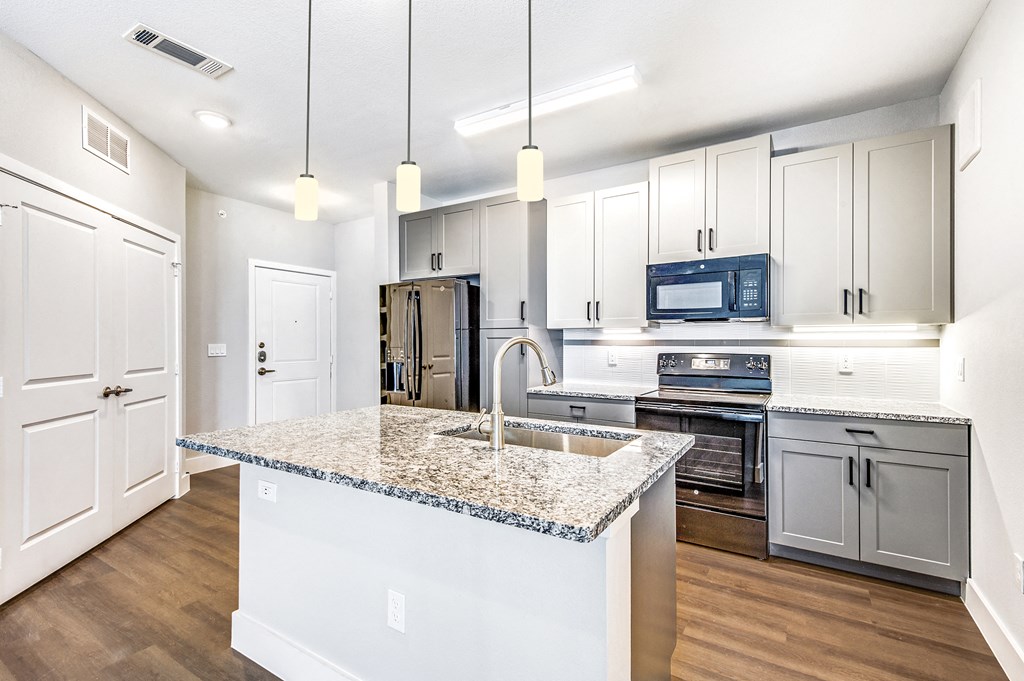 a kitchen with white cabinets and a marble counter top