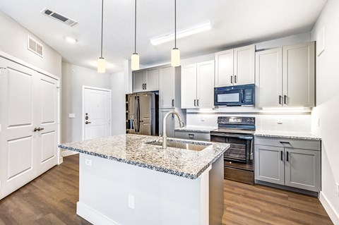 a kitchen with white cabinets and a marble counter top