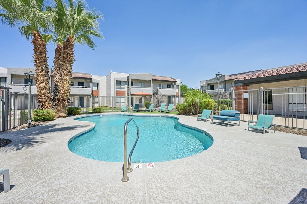 A swimming pool surrounded by palm trees and lounge chairs.