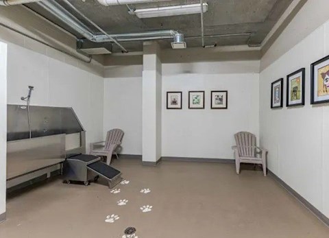 A room with a fridge, two chairs and pictures on the wall.