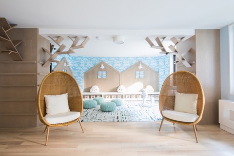 two chairs in a nursery with a house mural on the wall