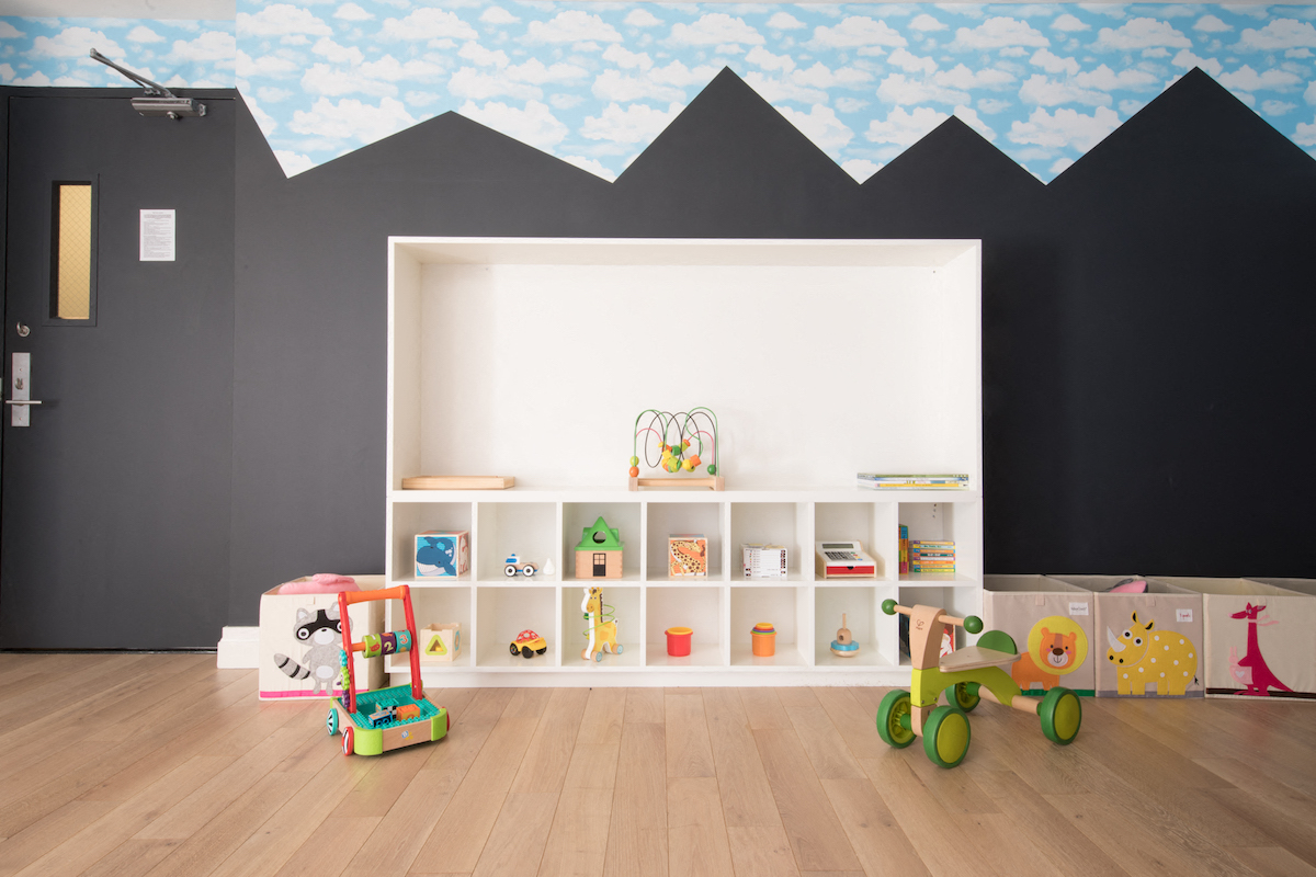 a childs playroom with toys and shelves and a wall mural of mountains