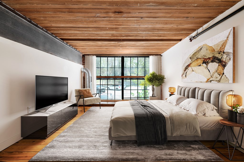 Modern bedroom with exposed wood ceiling, large windows, and abstract art.
