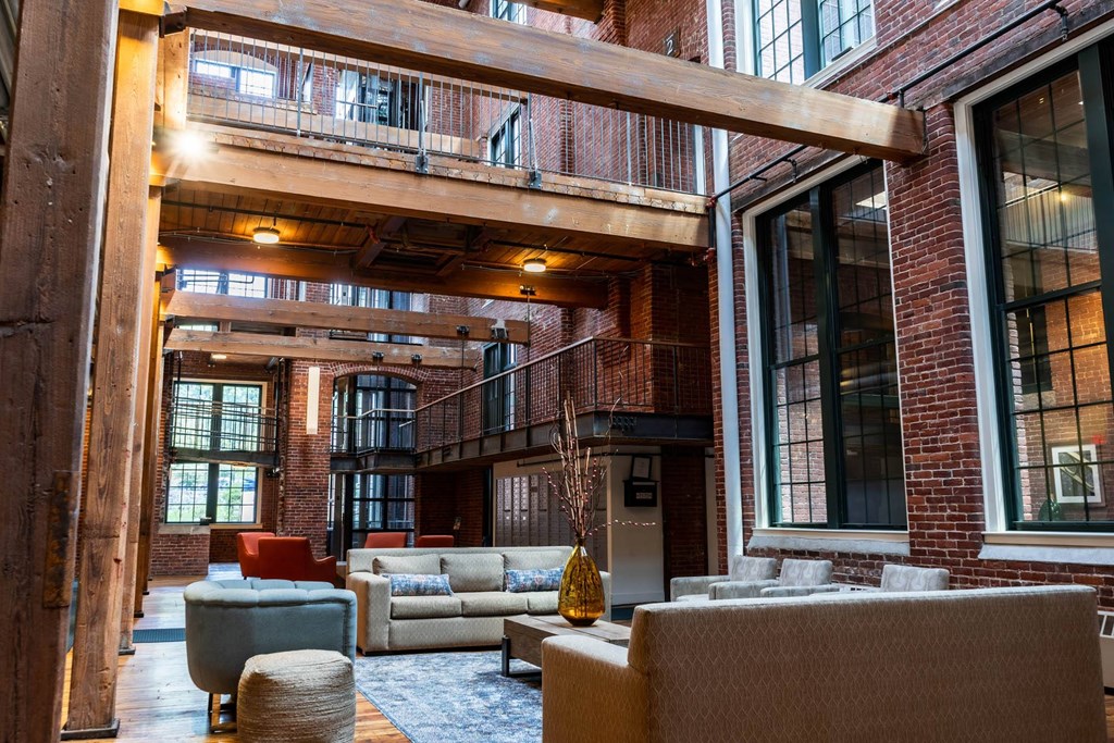 Spacious lounge area with exposed brick, wooden beams, and comfortable seating.