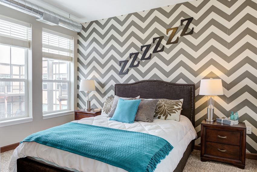 a bedroom with a bed and a chevron wallpaper