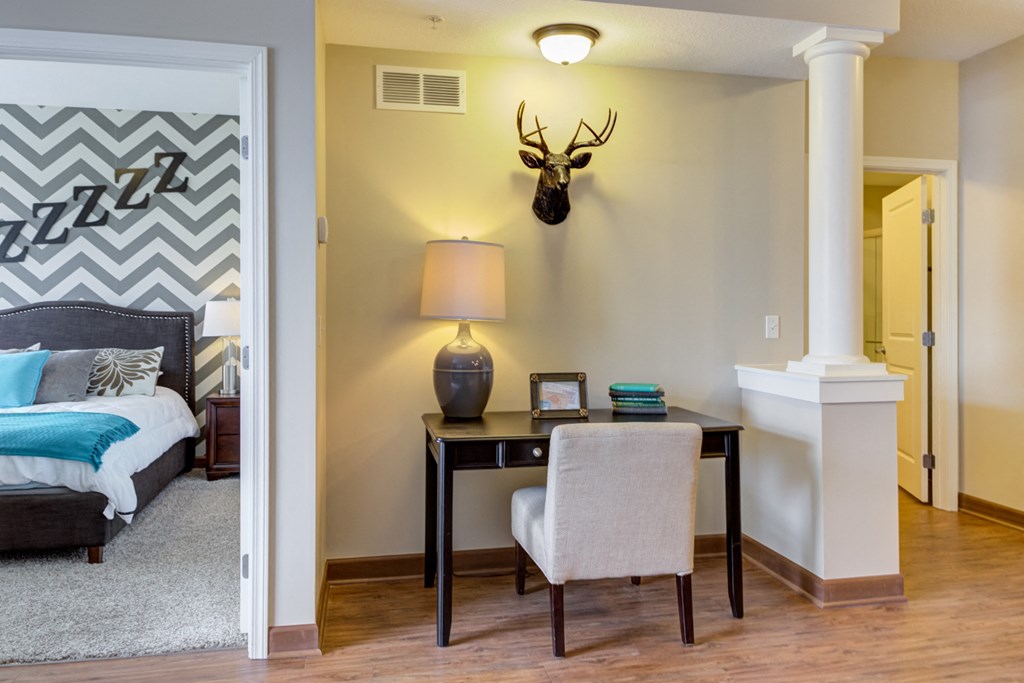 a bedroom with a desk and a deer head on the wall