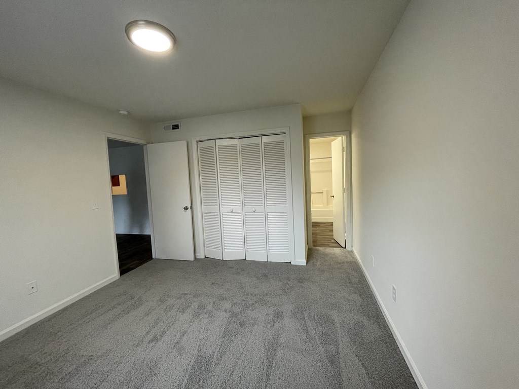 an empty living room with a closet and a door to a bathroom