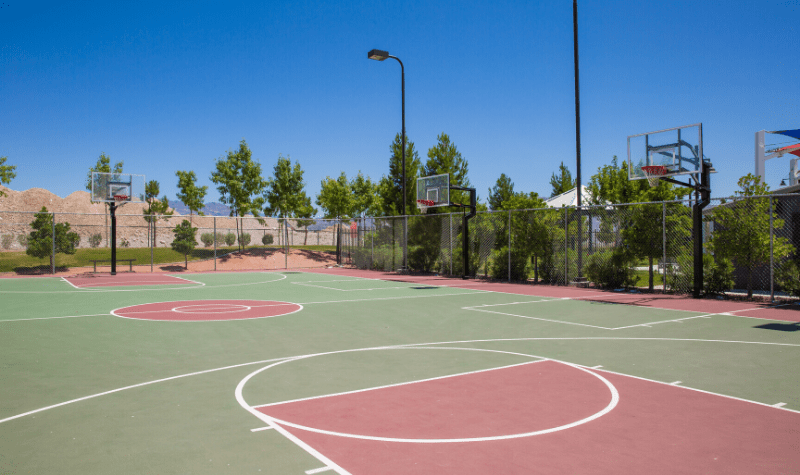 a basketball court in a park with trees
