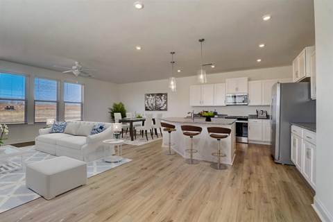 A modern kitchen with white cabinets and a wooden floor.