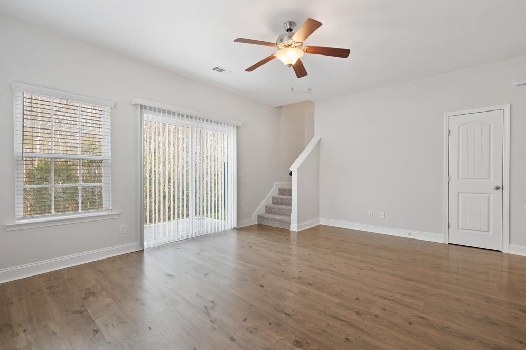 Harris Trail Luxury Townhomes for rent Richmond Hill, GA photo of an empty living room with white walls and a ceiling fan