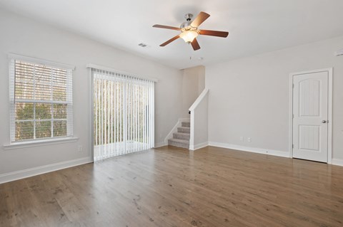 Harris Trail Luxury Townhomes for rent Richmond Hill, GA photo of an empty living room with white walls and a ceiling fan