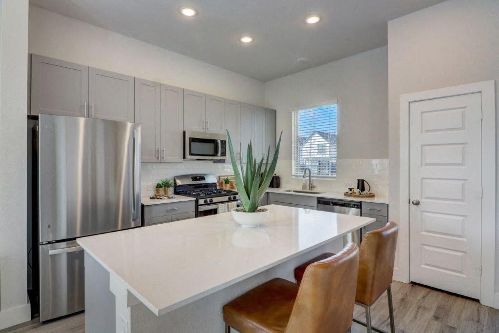 a kitchen with a white counter top and a stainless steel refrigerator