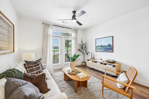 A living room with a white couch, a wooden chair, a coffee table, and a painting on the wall.