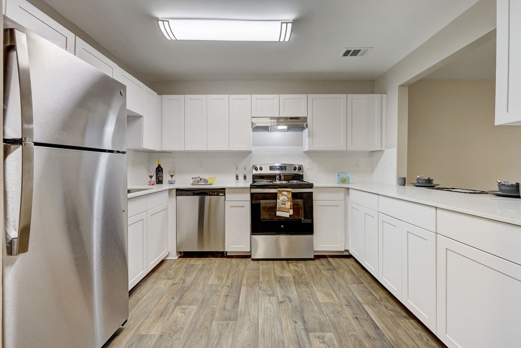 Sandy Springs, GA Apartments – Celebration at Sandy Springs - renovated kitchen with white cabinets, stainless-steel appliances and hardwood floors