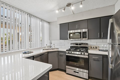 A modern kitchen with a white countertop and stainless steel appliances.