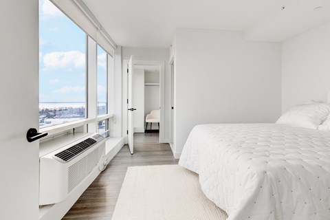 A bedroom with a large bed and a window with a view of the city.