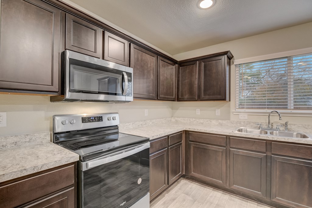an empty kitchen with a stove microwave and sink
