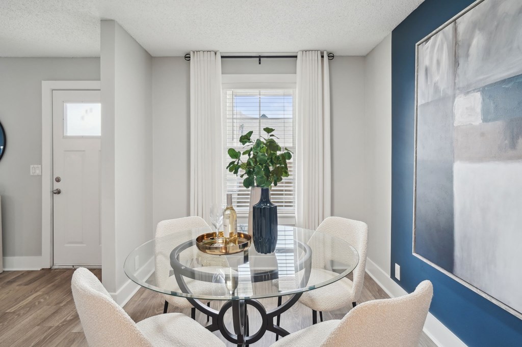 Dining room with glass table, white chairs, and modern decor.