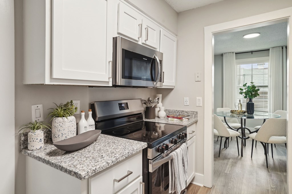 Modern kitchen with white cabinets, stainless steel appliances, and a view into the dining area.