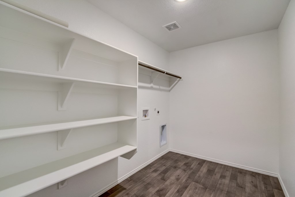 a room with white walls and shelves and a wood floor