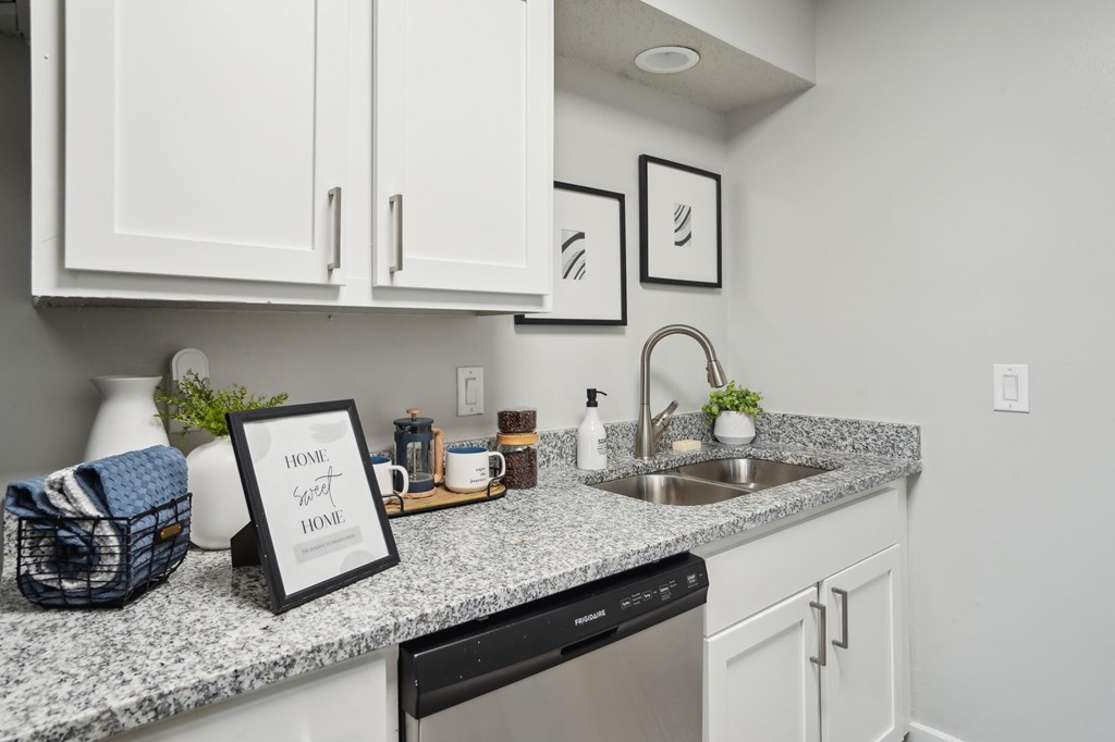 Modern kitchen with white cabinets, granite countertops, stainless steel sink and appliances, and decorative accents.