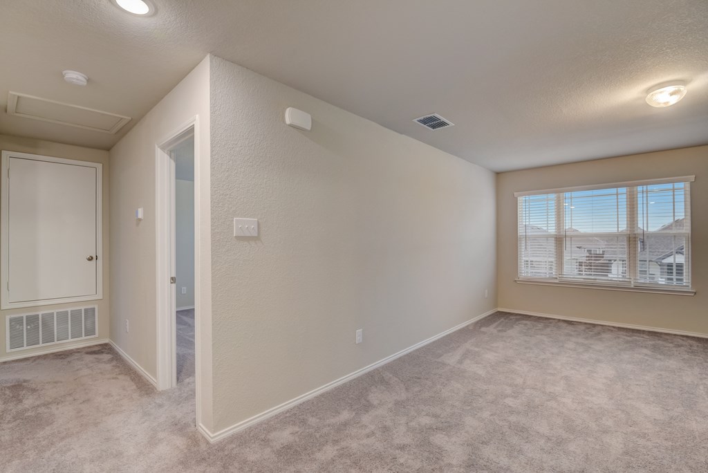 an empty living room with a large window and carpeting