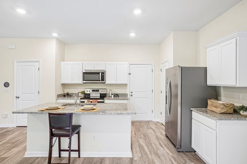 A kitchen with a table and chairs in front of a counter.