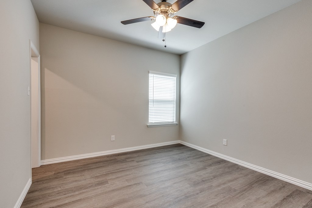 an empty room with a ceiling fan and a window
