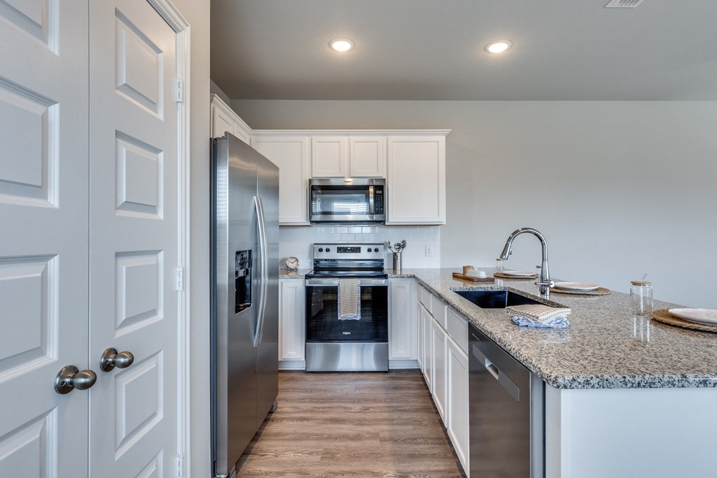 1-Bedroom Homes for Rent in Fort Worth, TX - Cottages at Summer Creek - Modern Kitchen with White Cabinetry, Stainless Steel Appliances, Granite Countertops, a Pantry, Large Sink, and Expansive Cooking Space