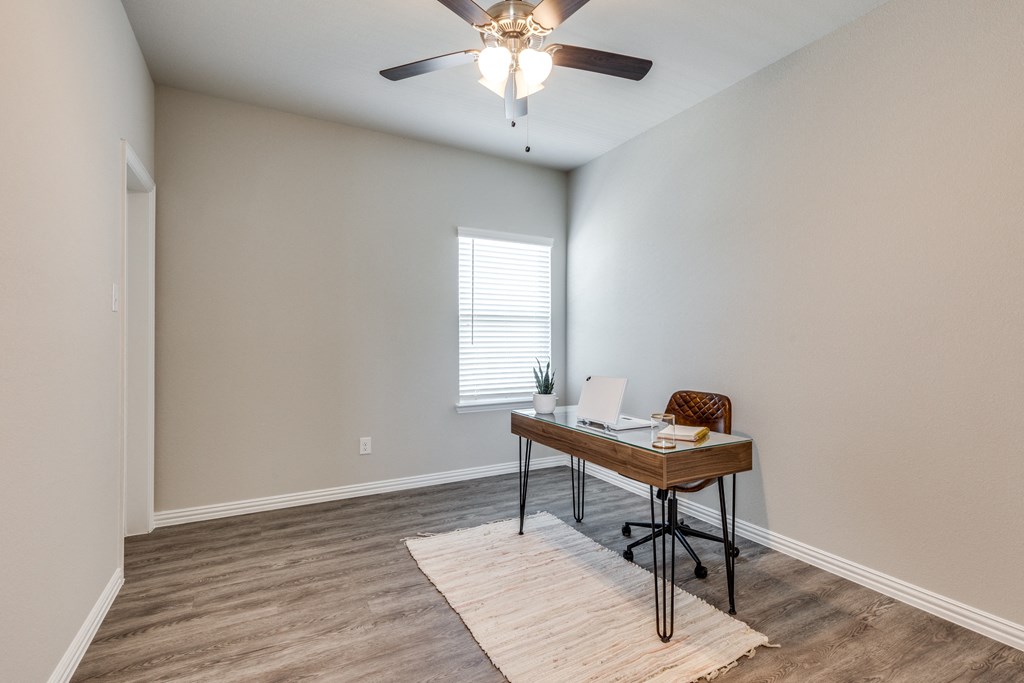 an empty room with a desk and a ceiling fan